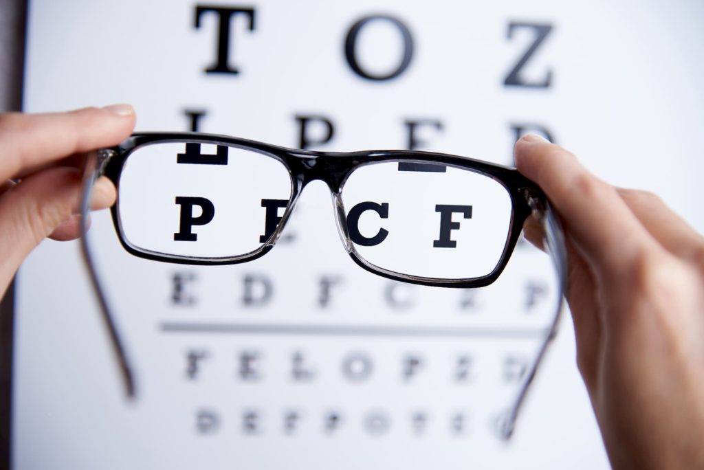 glasses held up to an eye test chart